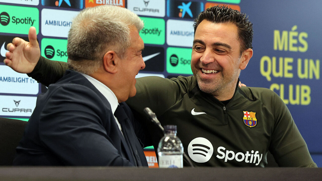 TOPSHOT - FC Barcelona President Joan Laporta (L) and Barcelona's Spanish coach Xavi react during a press conference at the Joan Gamper training ground in Sant Joan Despi, near Barcelona, on April 25, 2024. Xavi will remain as coach of Barcelona, the Spanish giants told AFP on April 24, despite having announced in January that he planned to quit at the end of the season due to the "cruel and unpleasant" nature of the job.