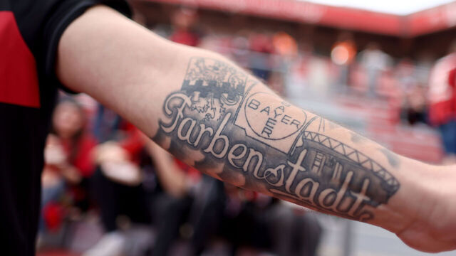 14 April 2024, North Rhine-Westphalia, Leverkusen: Soccer: Bundesliga, Bayer 04 Leverkusen - SV Werder Bremen, Matchday 29, BayArena. A Leverkusen fan shows a tattoo.IMPORTANT NOTE: In accordance with the regulations of the DFL German Football League and the DFB German Football Association, it is prohibited to exploit or have exploited photographs taken in the stadium and/or of the match in the form of sequential images and/or video-like photo series. Photo: Rolf Vennenbernd/dpa