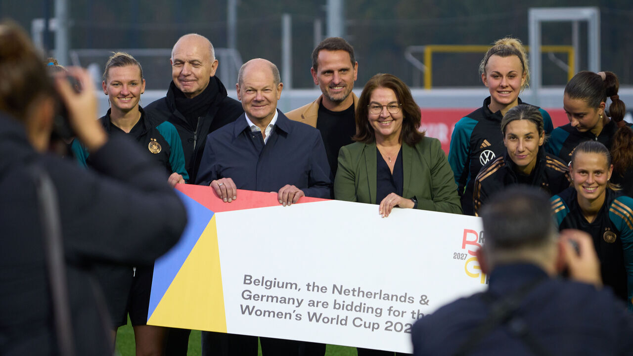 24 October 2023, Hesse, Frankfurt/Main: German Chancellor Olaf Scholz (SPD, M) holds a banner with the team during a visit to the women's national soccer team's training session at the DFB campus to bid for the 2027 Women's World Cup. Photo: Thomas Frey/dpa