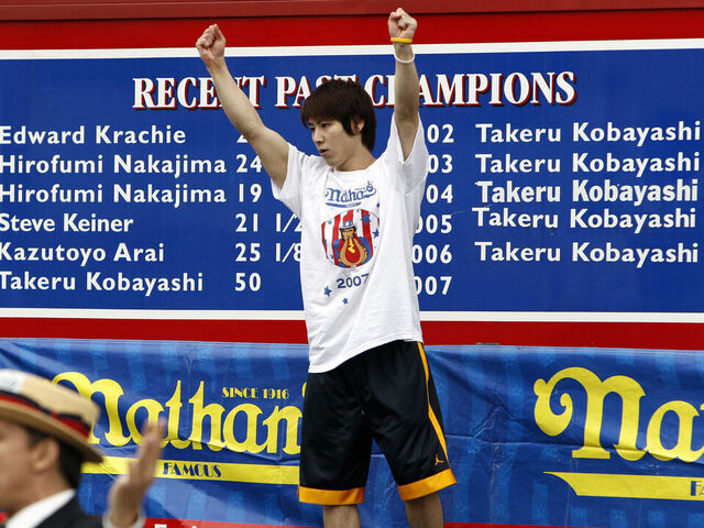 Brooklyn, UNITED STATES: Takeru Kobayashi of Nagano, Japan is introduced in front of a billboard showing his six consecutive wins and number of hot dogs ate during the annual International July Fourth Hot Dog Eating Contest, 04 July 2007, at the original Nathan?s Famous restaurant in the Coney Island section of Brooklyn, NY. Joey Chestnut of San Jose, California won by eating 66 hot dogs in 12 minutes, a world record, beating defending and six-time champion Kobayashi. The initial count was tied at 63 after the 12 minutes, but judges awarded Chestnut 3 more hot dogs after counting their plates. AFP PHOTO/Stan HONDA