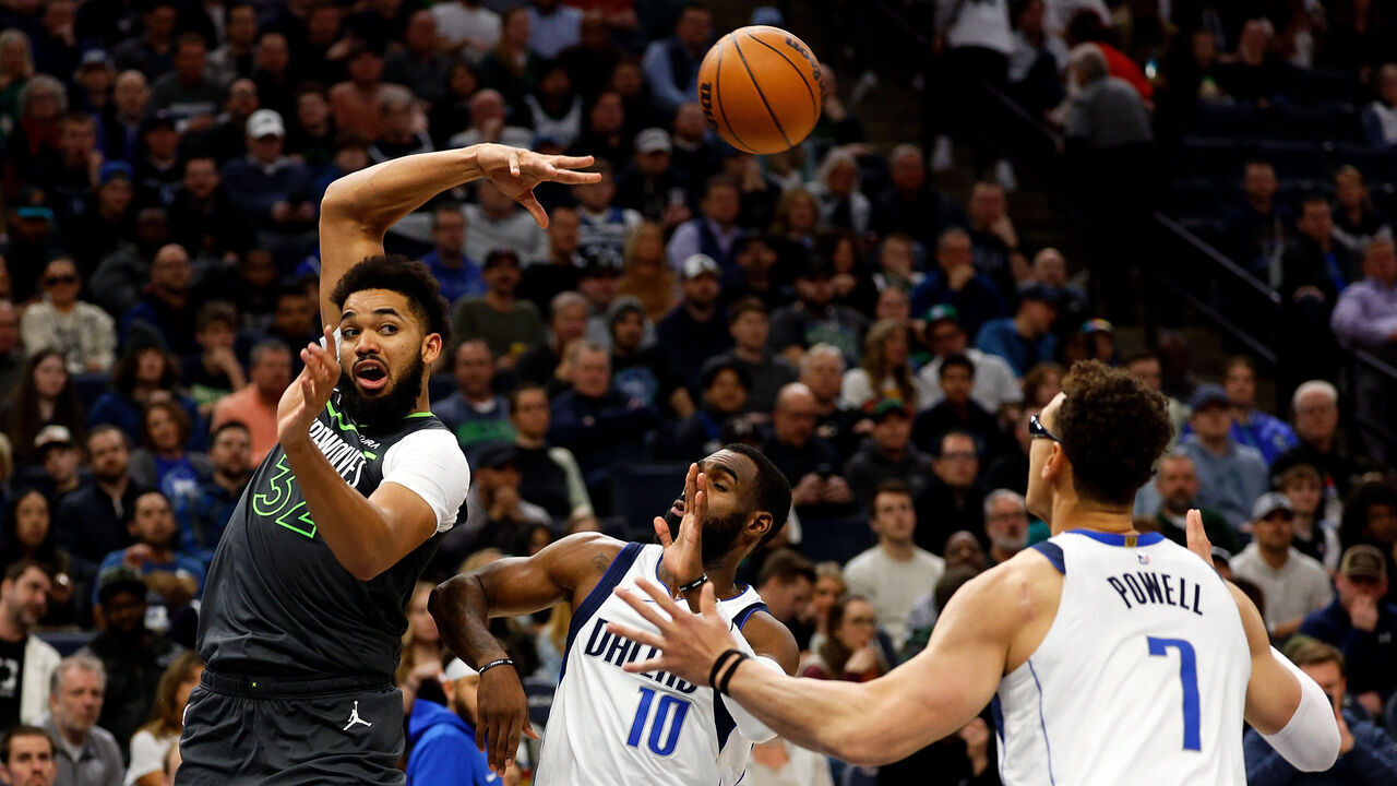 MINNEAPOLIS, MINNESOTA - JANUARY 31: Karl-Anthony Towns #32 of the Minnesota Timberwolves passes the ball while Tim Hardaway Jr. #10 and Dwight Powell #7 of the Dallas Mavericks defend in the third quarter at Target Center on January 31, 2024 in Minneapolis, Minnesota. The Timberwolves defeated the Mavericks 121-87.