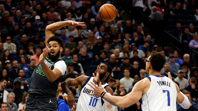 MINNEAPOLIS, MINNESOTA - JANUARY 31: Karl-Anthony Towns #32 of the Minnesota Timberwolves passes the ball while Tim Hardaway Jr. #10 and Dwight Powell #7 of the Dallas Mavericks defend in the third quarter at Target Center on January 31, 2024 in Minneapolis, Minnesota. The Timberwolves defeated the Mavericks 121-87.