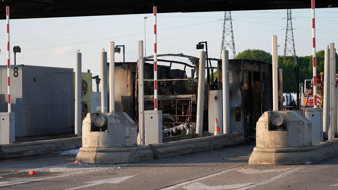 The charred remains of a bus sits at an A1 motorway toll in Fresnes-les-Montauban in Northern France, after a clash occurred on the roadway between supporters of Paris Saint-Germain (PSG) and Olympique Lyonnais (OL) football teams as they were travelling to Villeneuve d'Ascq near Lille for the French Cup football match final, on May 25, 2024. A bus caught fire and 20 participants were lightly injured in clashes between OL and PSG supporters at a motorway toll near Arras, hours before the French cup final opposing the two teams.