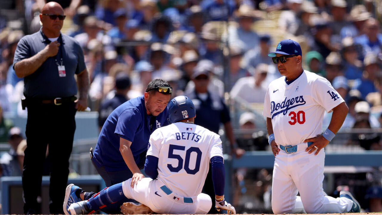 LOS ANGELES, CALIFORNIA - JUNE 16: Mookie Betts #50 of the Los Angeles Dodgers is tended to by medical personnel and Manager Dave Roberts #30 after getting hit by a pitch during the seventh inning against the Kansas City Royals at Dodger Stadium on June 16, 2024 in Los Angeles, California.