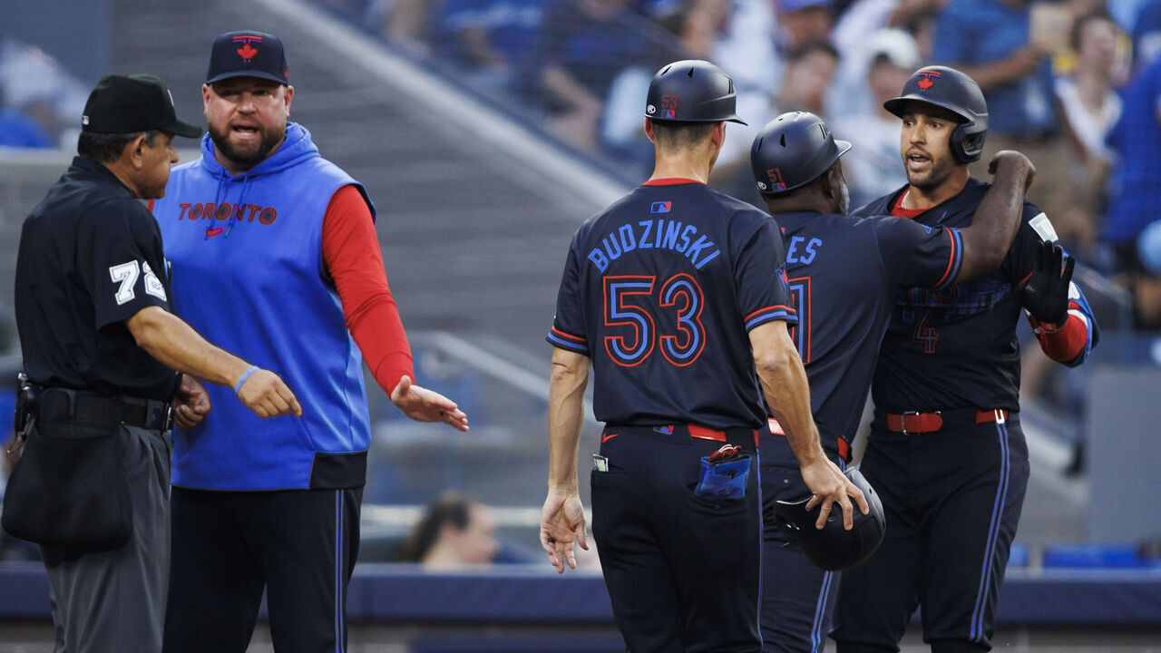 TORONTO, CANADA - JUNE 19: George Springer #4 of the Toronto Blue Jays is held back by coaches Carlos Febles #51 and Mark Budzinski #53 as manager John Schneider talks with home plate umpire Alfonso Marquez #72 in the third inning of their MLB game against the Boston Red Sox at Rogers Centre on June 19, 2024 in Toronto, Ontario, Canada.