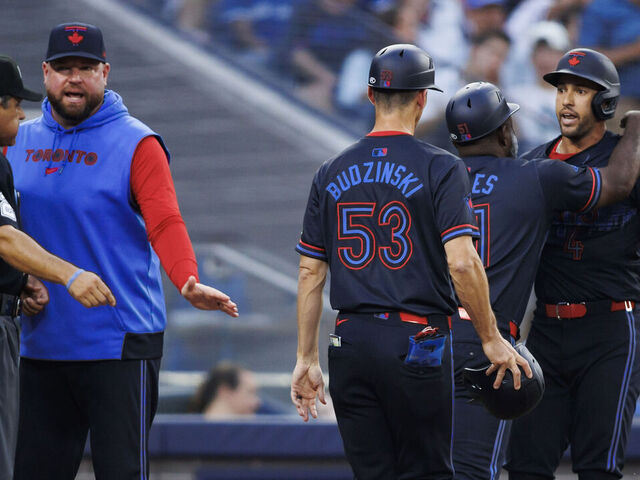 TORONTO, CANADA - JUNE 19: George Springer #4 of the Toronto Blue Jays is held back by coaches Carlos Febles #51 and Mark Budzinski #53 as manager John Schneider talks with home plate umpire Alfonso Marquez #72 in the third inning of their MLB game against the Boston Red Sox at Rogers Centre on June 19, 2024 in Toronto, Ontario, Canada.