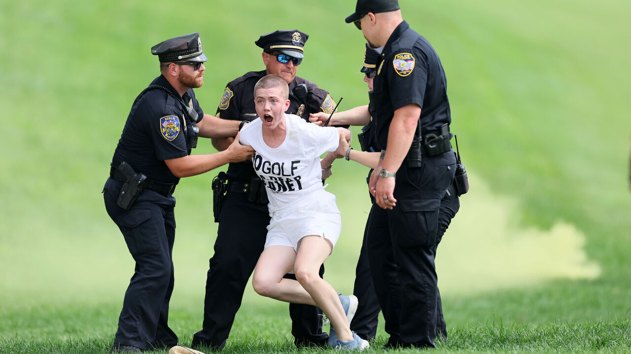 CROMWELL, CONNECTICUT - JUNE 23: Climate change protestors are ushered off the 18th green by police officers during the final round of the Travelers Championship at TPC River Highlands on June 23, 2024 in Cromwell, Connecticut.