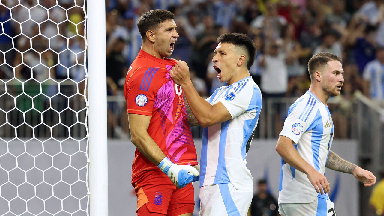 Argentina's goalkeeper #23 Emiliano Martinez (L) celebrates with Argentina's defender #25 Lisandro Martinez (C) after Ecuador's forward #13 Enner Valencia (out of frame) missed a goal from the penalty spot during the Conmebol 2024 Copa America tournament quarter-final football match between Argentina and Ecuador at NRG Stadium in Houston, Texas, on July 4, 2024.
