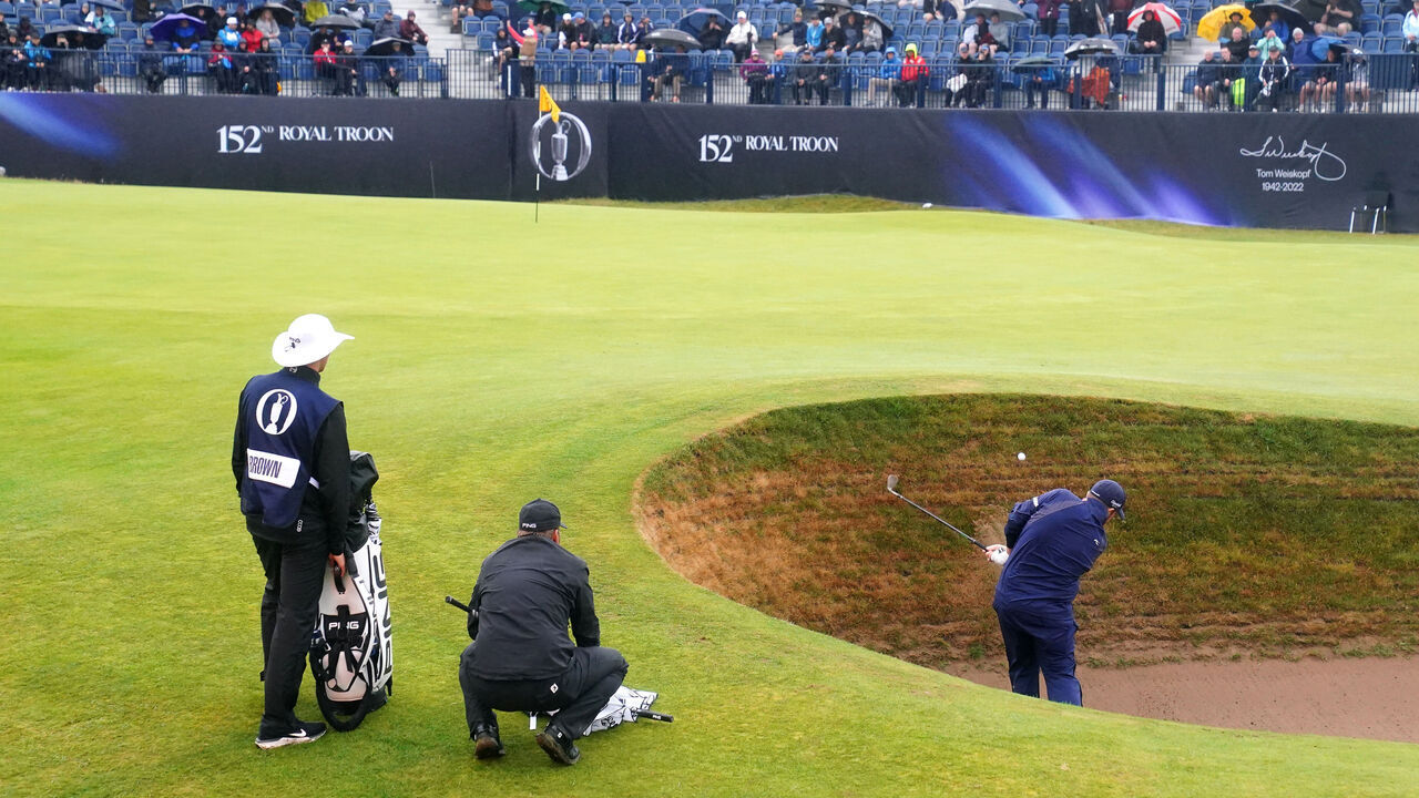 Ireland's Shane Lowry chips out of a bunker on the 17th as England's Daniel Brown watches on during day three of The Open at Royal Troon, South Ayrshire, Scotland. Picture date: Saturday July 20, 2024.