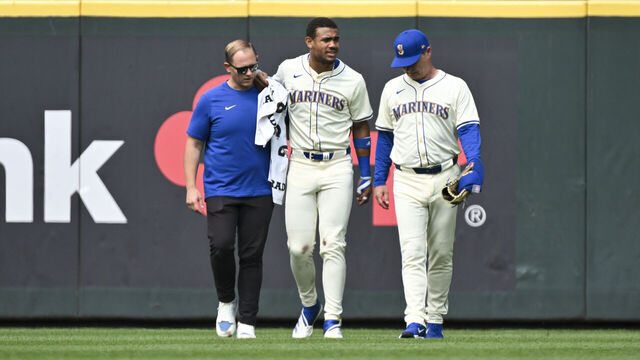 SEATTLE, WASHINGTON - JULY 21: Julio Rodriguez #44 of the Seattle Mariners is helped off the field by manager Scott Servais and the athletic training staff during the sixth inning against the Houston Astros at T-Mobile Park on July 21, 2024 in Seattle, Washington.
