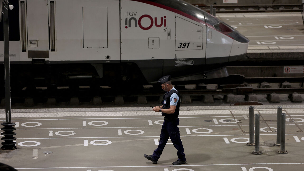 A French gendarme walks on a platform near an InOui high-speed TGV train at the Gare Montparnasse train station in Paris on July 26, 2024 as France's high-speed rail network was hit by malicious acts disrupting the transport system hours before the opening ceremony of the Paris 2024 Olympic Games. According to SNCF a massive attack on a large scale hit the TGV network and many routes will have to be cancelled. SNCF urged passengers to postpone their trips and stay away from train stations.