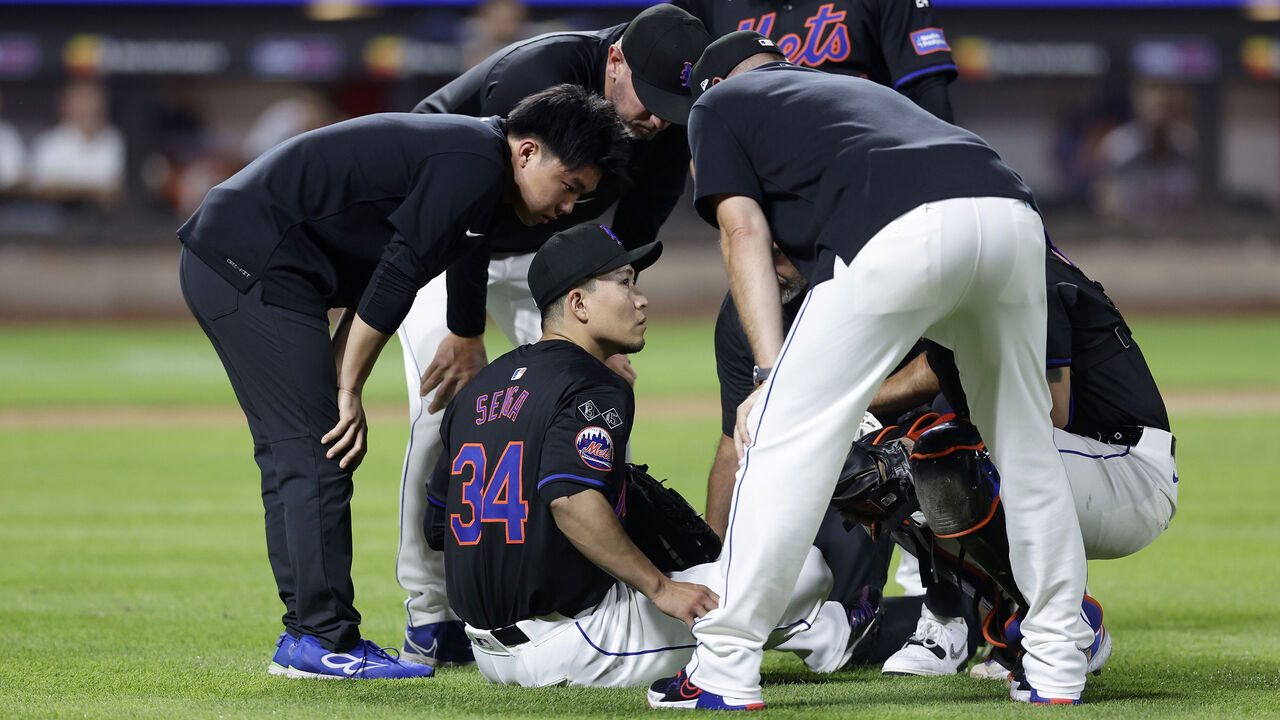 NEW YORK, NEW YORK - JULY 26: Kodai Senga #34 of the New York Mets sits on the field and is checked out by team staff after an injury during the sixth inning against the Atlanta Braves at Citi Field on July 26, 2024 in New York City.