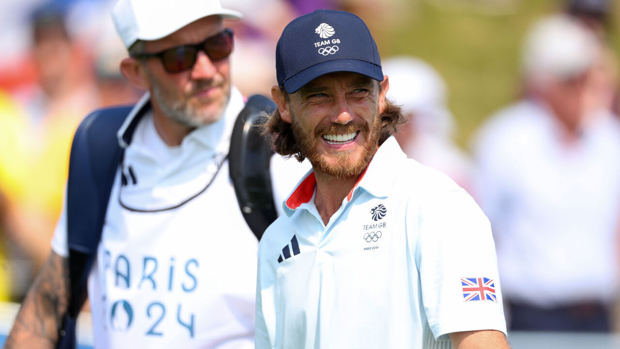 PARIS, FRANCE - AUGUST 02: Tommy Fleetwood of Team Great Britain smiles alongside his caddie, Ian Finnis (obscured) on the first hole during Day Two of the Men's Individual Stroke Play on day seven of the Olympic Games Paris 2024 at Le Golf National on August 02, 2024 in Paris, France.