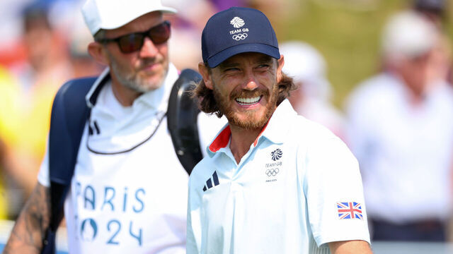 PARIS, FRANCE - AUGUST 02: Tommy Fleetwood of Team Great Britain smiles alongside his caddie, Ian Finnis (obscured) on the first hole during Day Two of the Men's Individual Stroke Play on day seven of the Olympic Games Paris 2024 at Le Golf National on August 02, 2024 in Paris, France.