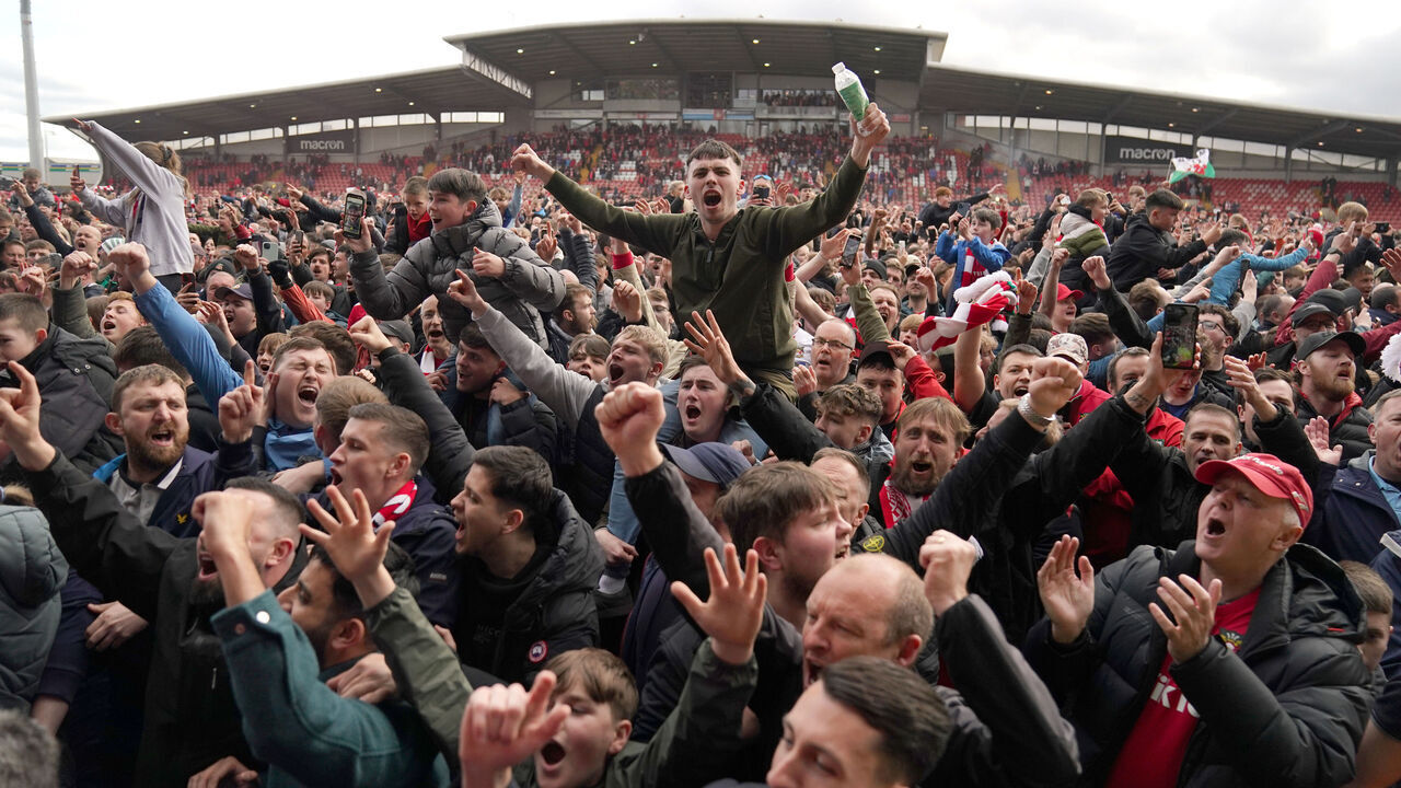 Wrexham fans on the pitch celebrating promotion to League One after the final whistle of the Sky Bet League Two match at the SToK Cae Ras, Wrexham. Picture date: Saturday April 13, 2024.