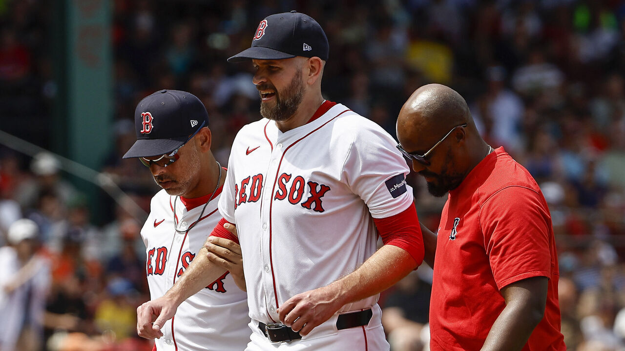 BOSTON, MA - AUGUST 11: Starting pitcher James Paxton #65 of the Boston Red Sox is helped off the field by manager Alex Cora #13, left, and a trainer after injuring himself running to cover first base during the first inning against the Houston Astros at Fenway Park on August 11, 2024 in Boston, Massachusetts.