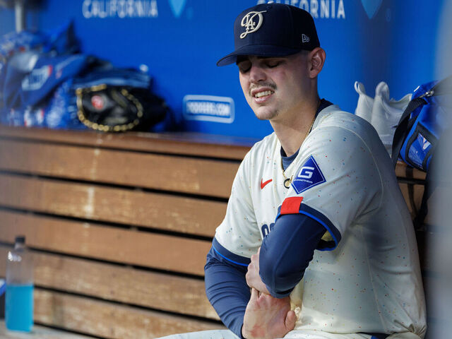 LOS ANGELES, CA - AUGUST 10, 2024: Los Angeles Dodgers starting pitcher River Ryan (77) stretches his right throwing arm in the dugout in the top of the fifth inning and was pulled from the game in the bottom of the fifth inning for a right arm injury against the Pittsburgh Pirates August 10, 2024 in Los Angeles, California. (Gina Ferazzi / Los Angeles Times via Getty Images)