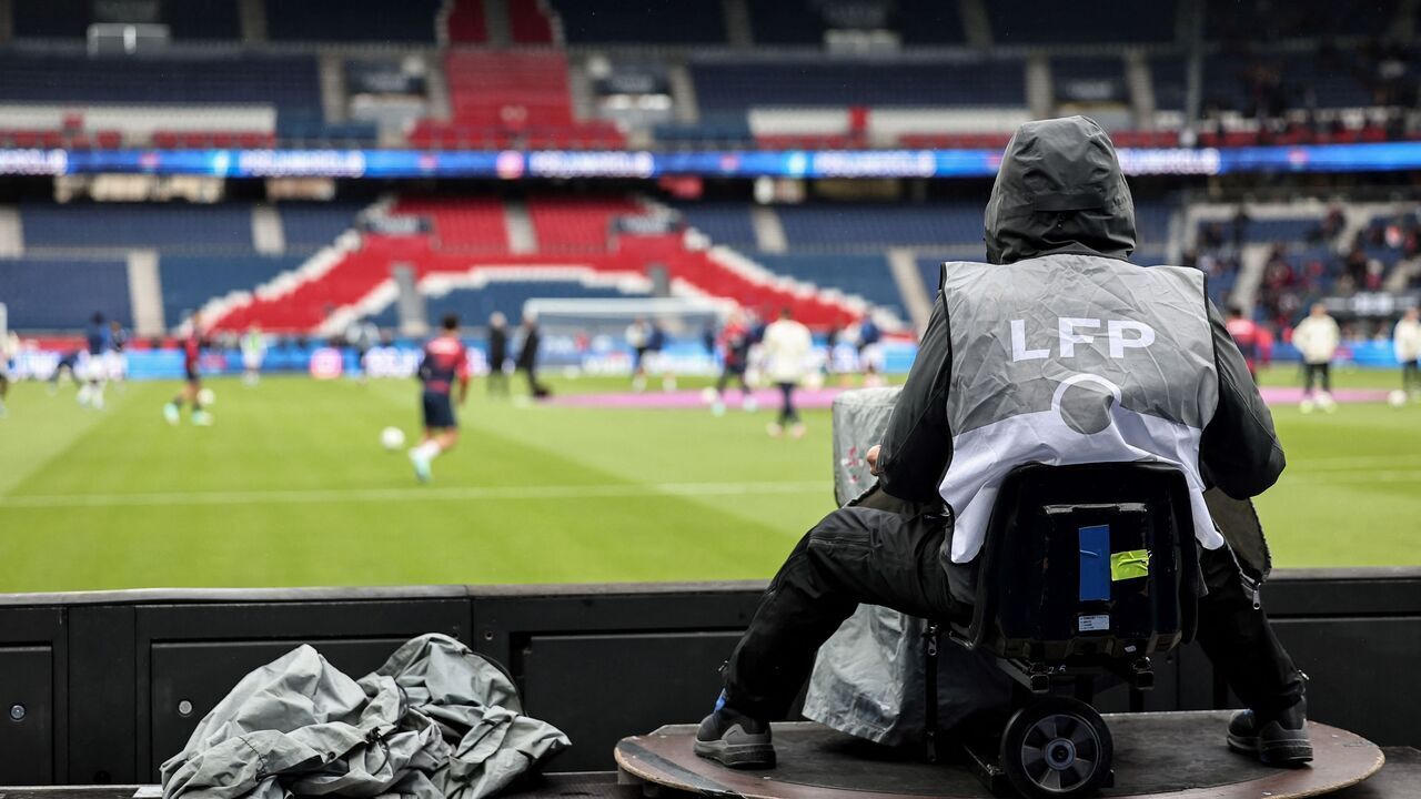 A TV cameraman sits behind his camera during the French L1 football match between Paris Saint-Germain (PSG) and Strasbourg at the Parc des Princes stadium in Paris on October 21, 2023.