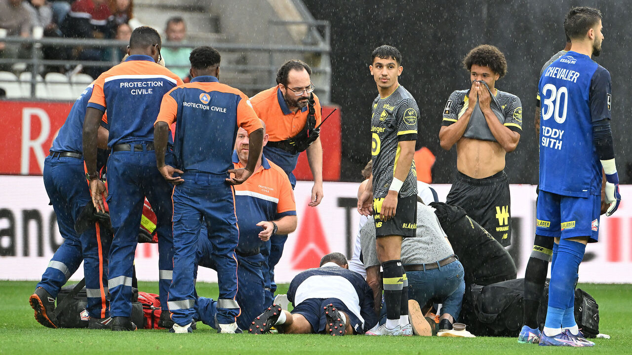 Lille's (R) players stand next to Lille's English forward Angel Gomes receiving medical attention as he lays on the pitch after being injured during the French L1 football match between Stade de Reims and Lille LOSC at the Stade Auguste-Delaune in Reims, northern France, on August 17, 2024.