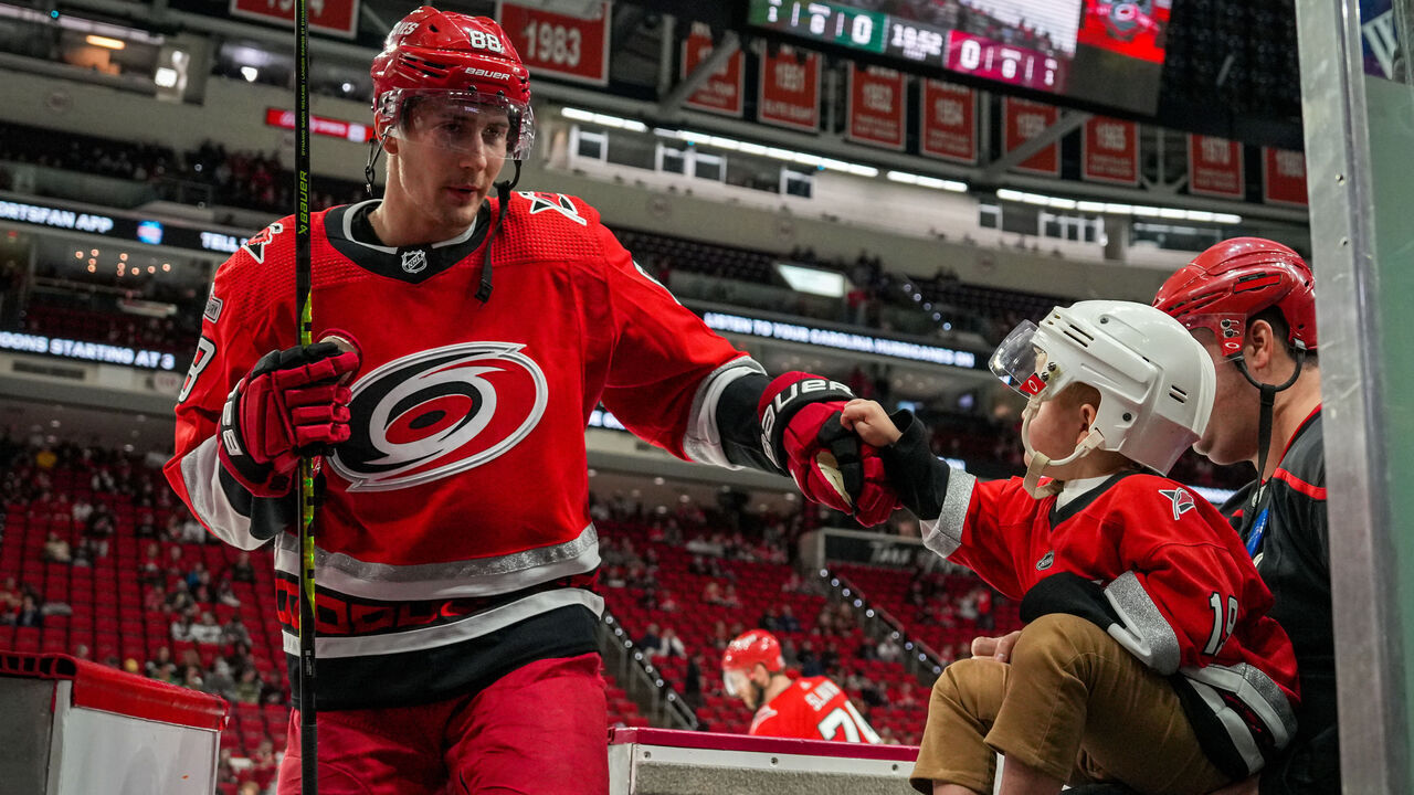 RALEIGH, NORTH CAROLINA - JANUARY 19: Martin Necas #88 of the Carolina Hurricanes greets a young fan after warmups prior to the game against the Minnesota Wild at PNC Arena on January 19, 2023 in Raleigh, North Carolina.