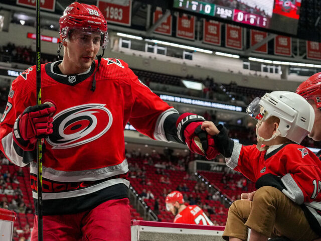 RALEIGH, NORTH CAROLINA - JANUARY 19: Martin Necas #88 of the Carolina Hurricanes greets a young fan after warmups prior to the game against the Minnesota Wild at PNC Arena on January 19, 2023 in Raleigh, North Carolina.