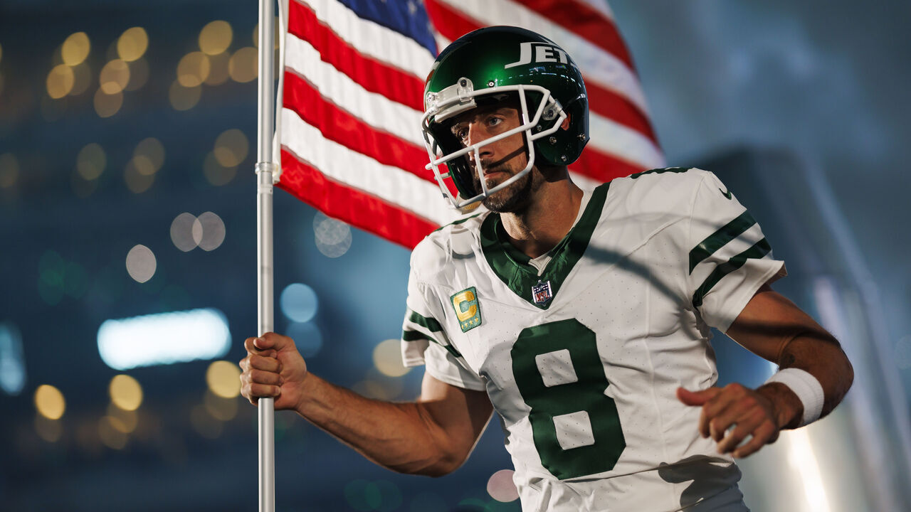 EAST RUTHERFORD, NEW JERSEY - SEPTEMBER 11: Aaron Rodgers #8 of the New York Jets runs onto the field with an American flag during player introductions prior to an NFL football game against the Buffalo Bills at MetLife Stadium on September 11, 2023 in East Rutherford, New Jersey.