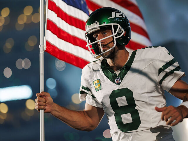 EAST RUTHERFORD, NEW JERSEY - SEPTEMBER 11: Aaron Rodgers #8 of the New York Jets runs onto the field with an American flag during player introductions prior to an NFL football game against the Buffalo Bills at MetLife Stadium on September 11, 2023 in East Rutherford, New Jersey.