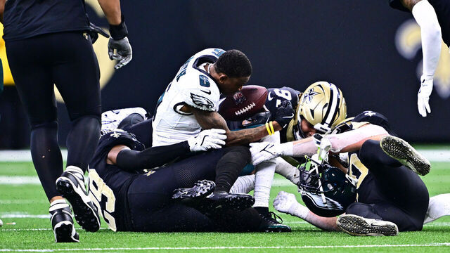 NEW ORLEANS, LOUISIANA - SEPTEMBER 22: DeVonta Smith #6 of the Philadelphia Eagles loses his helmet after being tackled by Paulson Adebo #29 and Kendal Vickers #91 of the New Orleans Saints at Caesars Superdome on September 22, 2024 in New Orleans, Louisiana.