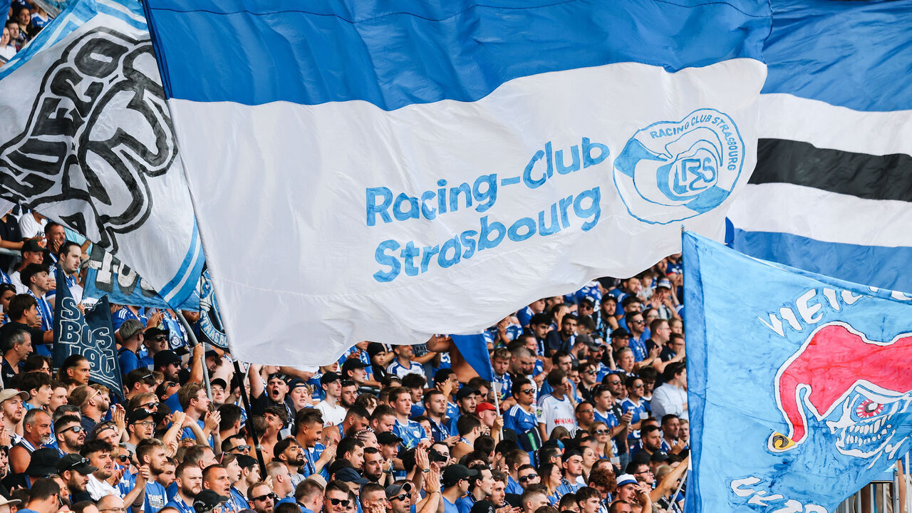 Strasbourg's supporters wave flags and cheer during the French L1 football match between RC Strasbourg Alsace and Stade Rennais FC at Stade de la Meinau in Strasbourg, eastern France on August 25, 2024.