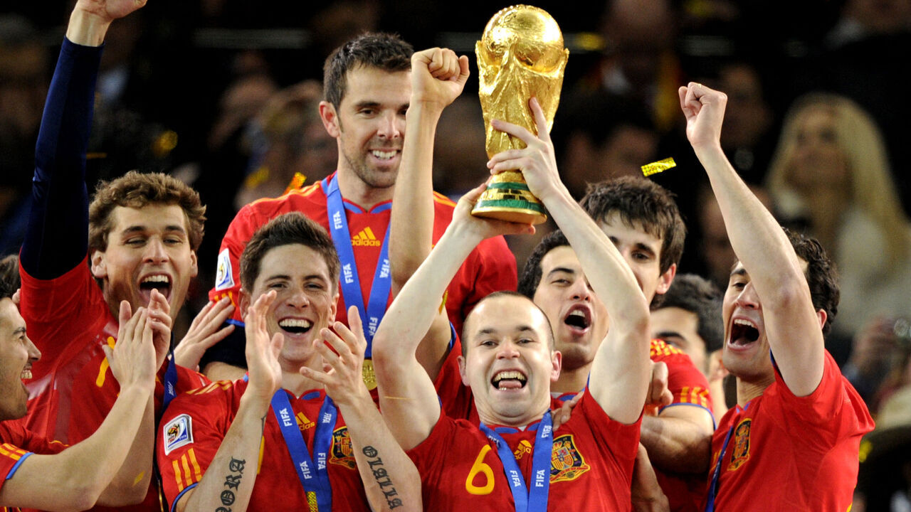 TOPSHOT - Spain's midfielder Andres Iniesta (C) raises the trophy as Spain's national football team players celebrate winning the 2010 World Cup football final Netherlands vs. Spain on July 11, 2010 at Soccer City stadium in Soweto, suburban Johannesburg. NO PUSH TO MOBILE / MOBILE USE SOLELY WITHIN EDITORIAL ARTICLE - AFP PHOTO / JAVIER SORIANO