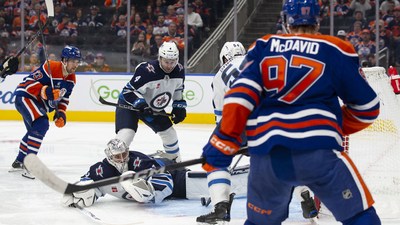 EDMONTON, CANADA - OCTOBER 9: Viktor Arvidsson #33 and Connor McDavid #97 of the Edmonton Oilers put pressure on goaltender Connor Hellebuyck #37 of the Winnipeg Jets during the second period of the season opener at Rogers Place on October 9, 2024 in Edmonton, Canada.