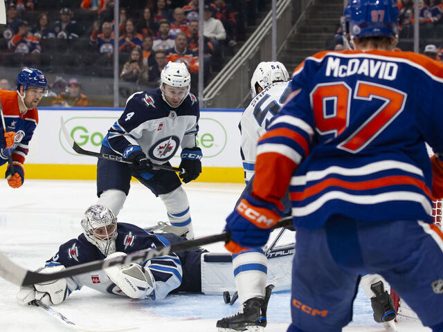 EDMONTON, CANADA - OCTOBER 9: Viktor Arvidsson #33 and Connor McDavid #97 of the Edmonton Oilers put pressure on goaltender Connor Hellebuyck #37 of the Winnipeg Jets during the second period of the season opener at Rogers Place on October 9, 2024 in Edmonton, Canada.