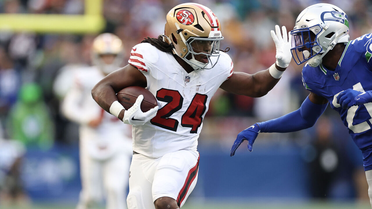 SEATTLE, WASHINGTON - OCTOBER 10: Jordan Mason #24 of the San Francisco 49ers runs the ball against Devon Witherspoon #21 of the Seattle Seahawks during the first quarter at Lumen Field on October 10, 2024 in Seattle, Washington.