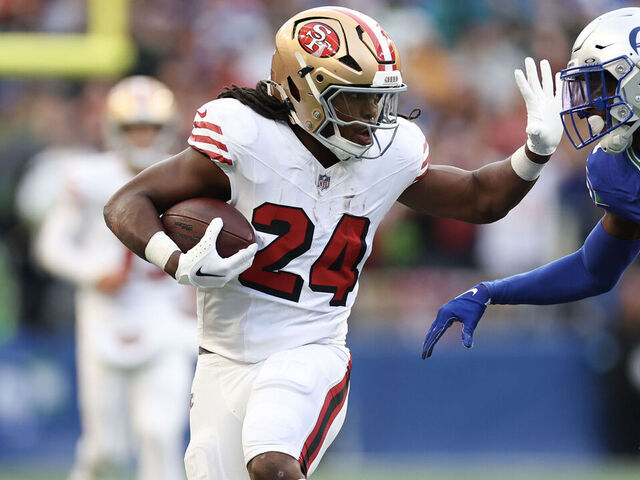 SEATTLE, WASHINGTON - OCTOBER 10: Jordan Mason #24 of the San Francisco 49ers runs the ball against Devon Witherspoon #21 of the Seattle Seahawks during the first quarter at Lumen Field on October 10, 2024 in Seattle, Washington.