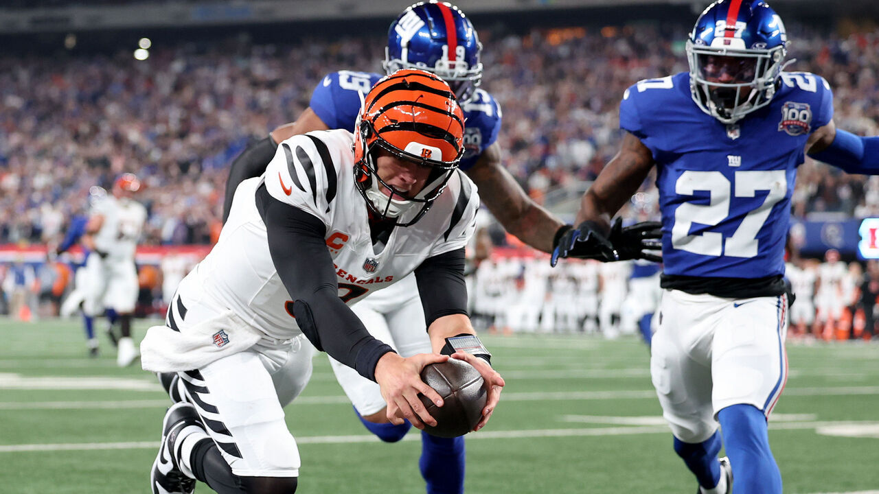 EAST RUTHERFORD, NEW JERSEY - OCTOBER 13: Joe Burrow #9 of the Cincinnati Bengals scores a touchdown against Isaiah Simmons #19 and Jason Pinnock #27 of the New York Giants during the first half at MetLife Stadium on October 13, 2024 in East Rutherford, New Jersey.
