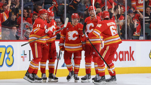 CALGARY, AB - OCTOBER 15: Matt Coronato #27 of the Calgary Flames celebrates with teammates Daniil Miromanov #62, Mikael Backlund #11 after a goal against PLAYER of the Chicago Blackhawks at Scotiabank Saddledome on October 15, 2024 in Calgary, Alberta, Canada.