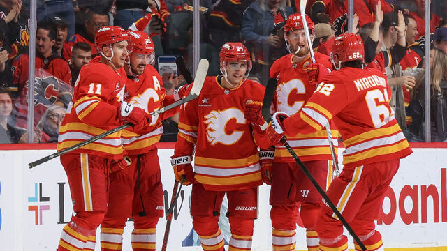 CALGARY, AB - OCTOBER 15: Matt Coronato #27 of the Calgary Flames celebrates with teammates Daniil Miromanov #62, Mikael Backlund #11 after a goal against PLAYER of the Chicago Blackhawks at Scotiabank Saddledome on October 15, 2024 in Calgary, Alberta, Canada.