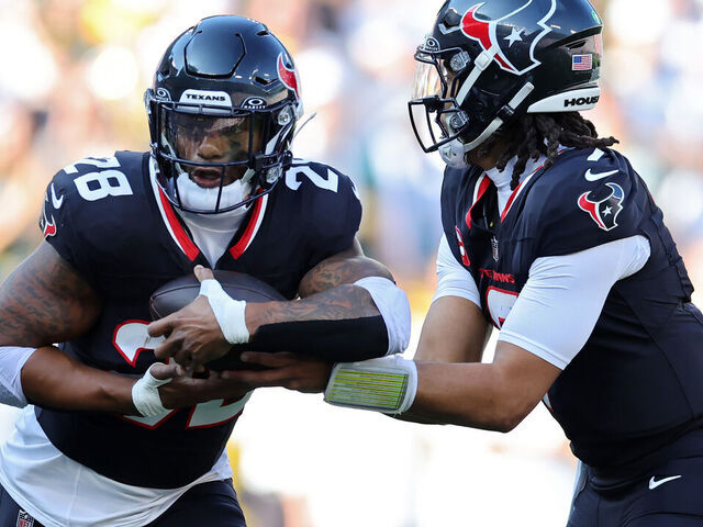GREEN BAY, WISCONSIN - OCTOBER 20: C.J. Stroud #7 hands the ball off to Joe Mixon #28 of the Houston Texans during the second quarter against the Green Bay Packers at Lambeau Field on October 20, 2024 in Green Bay, Wisconsin.