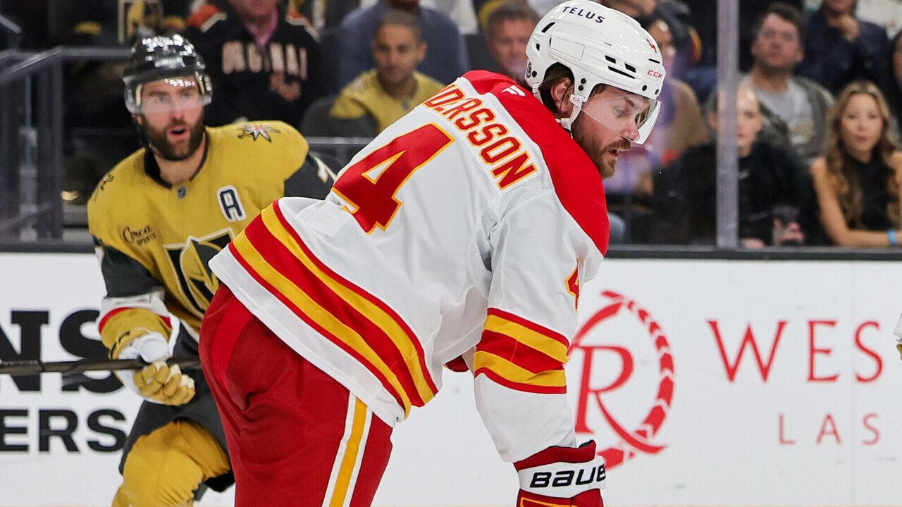 LAS VEGAS, NEVADA - OCTOBER 28: William Karlsson #71 of the Vegas Golden Knights and Rasmus Andersson #4 and Justin Kirkland #58 of the Calgary Flames vie for the puck in the second period of their game at T-Mobile Arena on October 28, 2024 in Las Vegas, Nevada. The Golden Knights defeated the Flames 5-0.