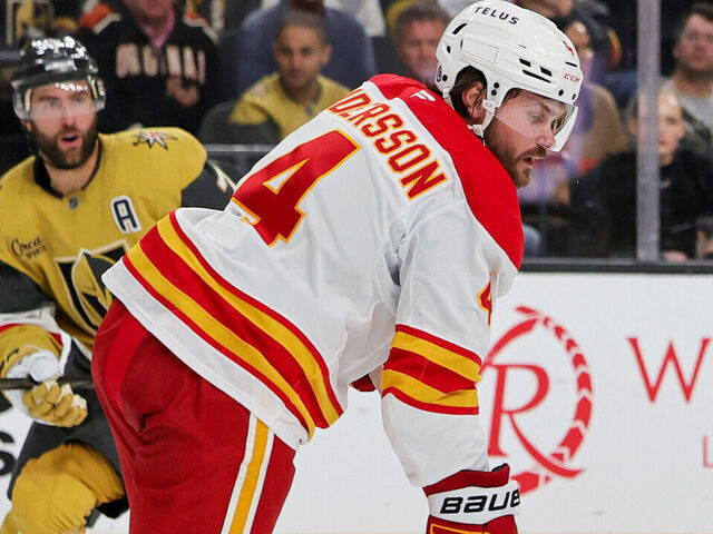 LAS VEGAS, NEVADA - OCTOBER 28: William Karlsson #71 of the Vegas Golden Knights and Rasmus Andersson #4 and Justin Kirkland #58 of the Calgary Flames vie for the puck in the second period of their game at T-Mobile Arena on October 28, 2024 in Las Vegas, Nevada. The Golden Knights defeated the Flames 5-0.
