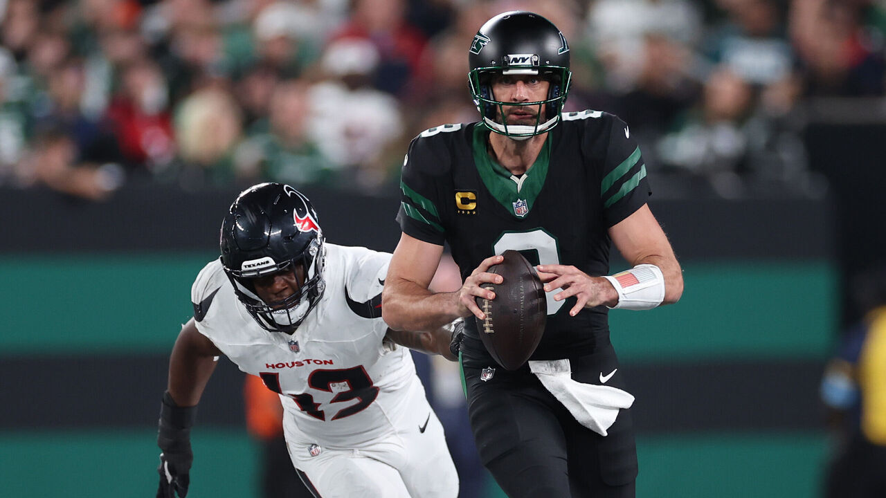 EAST RUTHERFORD, NEW JERSEY - OCTOBER 31: Aaron Rodgers #8 of the New York Jets is tackled by Neville Hewitt #43 of the Houston Texans during the third quarter at MetLife Stadium on October 31, 2024 in East Rutherford, New Jersey.
