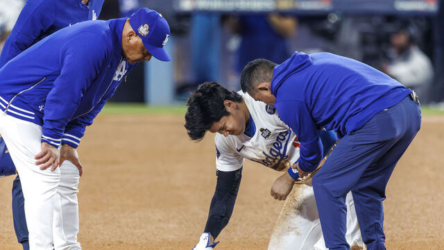 LOS ANGELES, CA - OCTOBER 26, 2024: Dodgers manager Dave Roberts, left, interpreter and trainer, right, attend to Los Angeles Dodgers designated hitter Shohei Ohtani (17) who partially dislocated his left shoulder while attempted to steal second base in the seventh inning against the Yankees in Game 2 of the World Series at Dodgers Stadium on October 26, 2024 in Los Angeles, California. (Gina Ferazzi / Los Angeles Times via Getty Images)