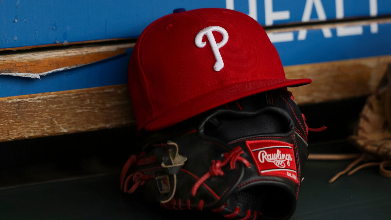 DETROIT, MICHIGAN - JUNE 26: A detail view of the Philadelphia Phillies logo on a hat and a Rawlings glove in the dugout prior to the start of the game against the Detroit Tigers at Comerica Park on June 26, 2024 in Detroit, Michigan.