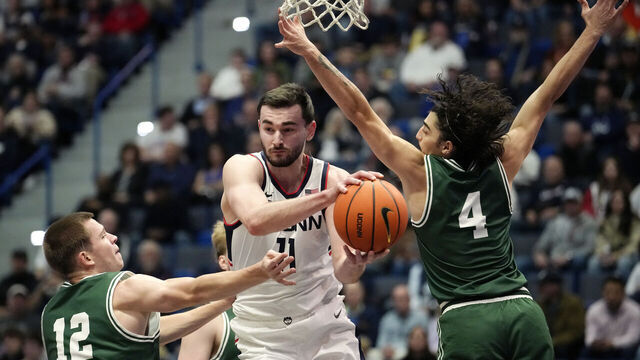 HARTFORD, CONNECTICUT - NOVEMBER 13: Alex Karaban #11 of the Connecticut Huskies is defended by Freds Pauls Bagatskis #12 and Zek Tekin #4 of the Le Moyne Dolphins during the first half of an NCAA basketball game at the XL Center on November 13, 2024 in Hartford, Connecticut.