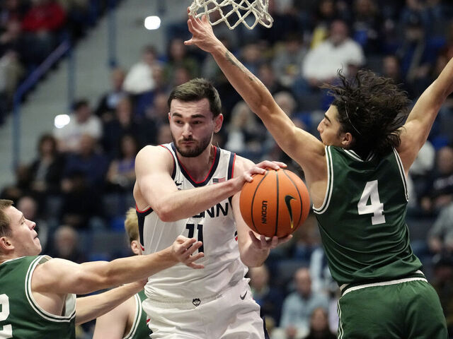 HARTFORD, CONNECTICUT - NOVEMBER 13: Alex Karaban #11 of the Connecticut Huskies is defended by Freds Pauls Bagatskis #12 and Zek Tekin #4 of the Le Moyne Dolphins during the first half of an NCAA basketball game at the XL Center on November 13, 2024 in Hartford, Connecticut.