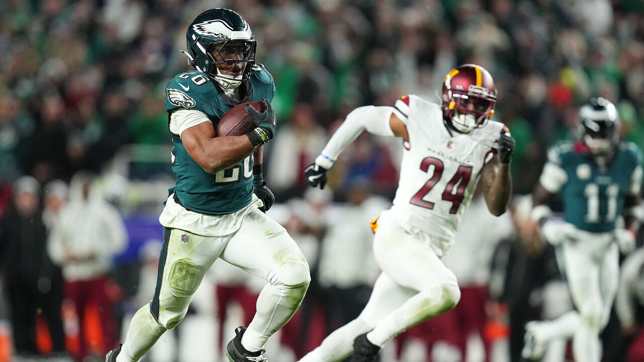 PHILADELPHIA, PENNSYLVANIA - NOVEMBER 14: Saquon Barkley #26 of the Philadelphia Eagles runs by Michael Davis #24 of the Washington Commanders on his way to a touchdown during the fourth quarter at Lincoln Financial Field on November 14, 2024 in Philadelphia, Pennsylvania.