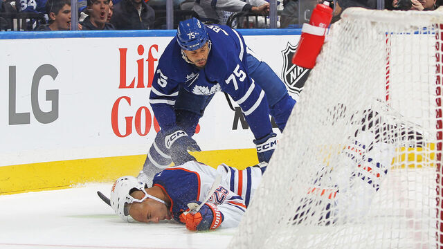 TORONTO, CANADA - NOVEMBER 16: Darnell Nurse #25 of the Edmonton Oilers is knocked to the ice by Ryan Reaves #75 of the Toronto Maple Leafs during the second period in an NHL game at Scotiabank Arena on November 16, 2024 in Toronto, Ontario, Canada.