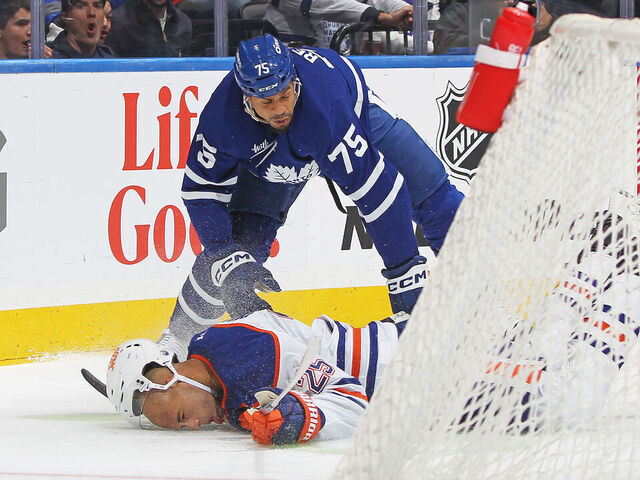 TORONTO, CANADA - NOVEMBER 16: Darnell Nurse #25 of the Edmonton Oilers is knocked to the ice by Ryan Reaves #75 of the Toronto Maple Leafs during the second period in an NHL game at Scotiabank Arena on November 16, 2024 in Toronto, Ontario, Canada.