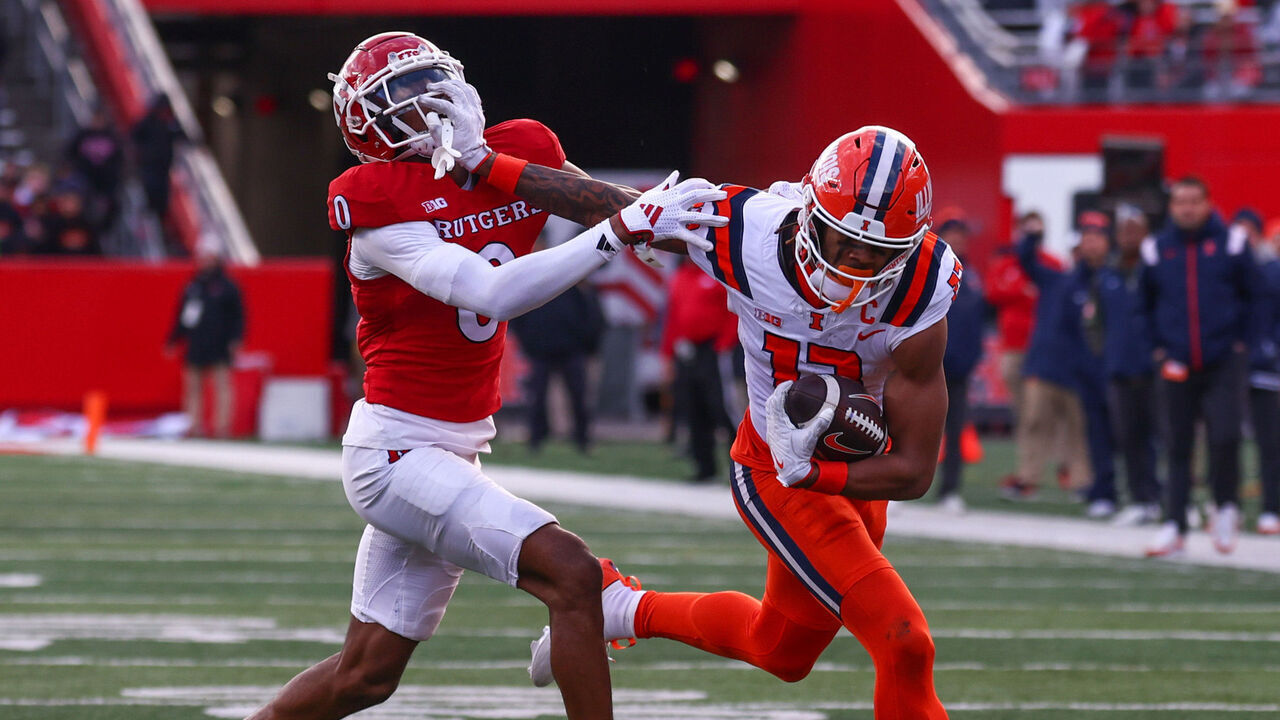 PISCATAWAY, NEW JERSEY - NOVEMBER 23: Pat Bryant #13 of the Illinois Fighting Illini runs with the ball while Eric Rogers #0 of the Rutgers Scarlet Knights attempts to tackle him during the second half at SHI Stadium on November 23, 2024 in Piscataway, New Jersey.