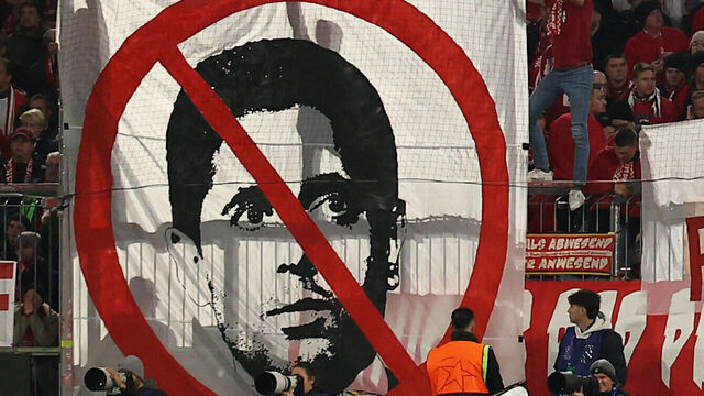 Bayern supporters hold banners including a crossed-out portrait of Paris Saint Germain's Qatari president Nasser al-Khelaifi during the UEFA Champions League, League phase - Matchday 5, football match between FC Bayern Munich Paris Saint-Germain (PSG) in Munich, southern Germany, on November 26, 2024.